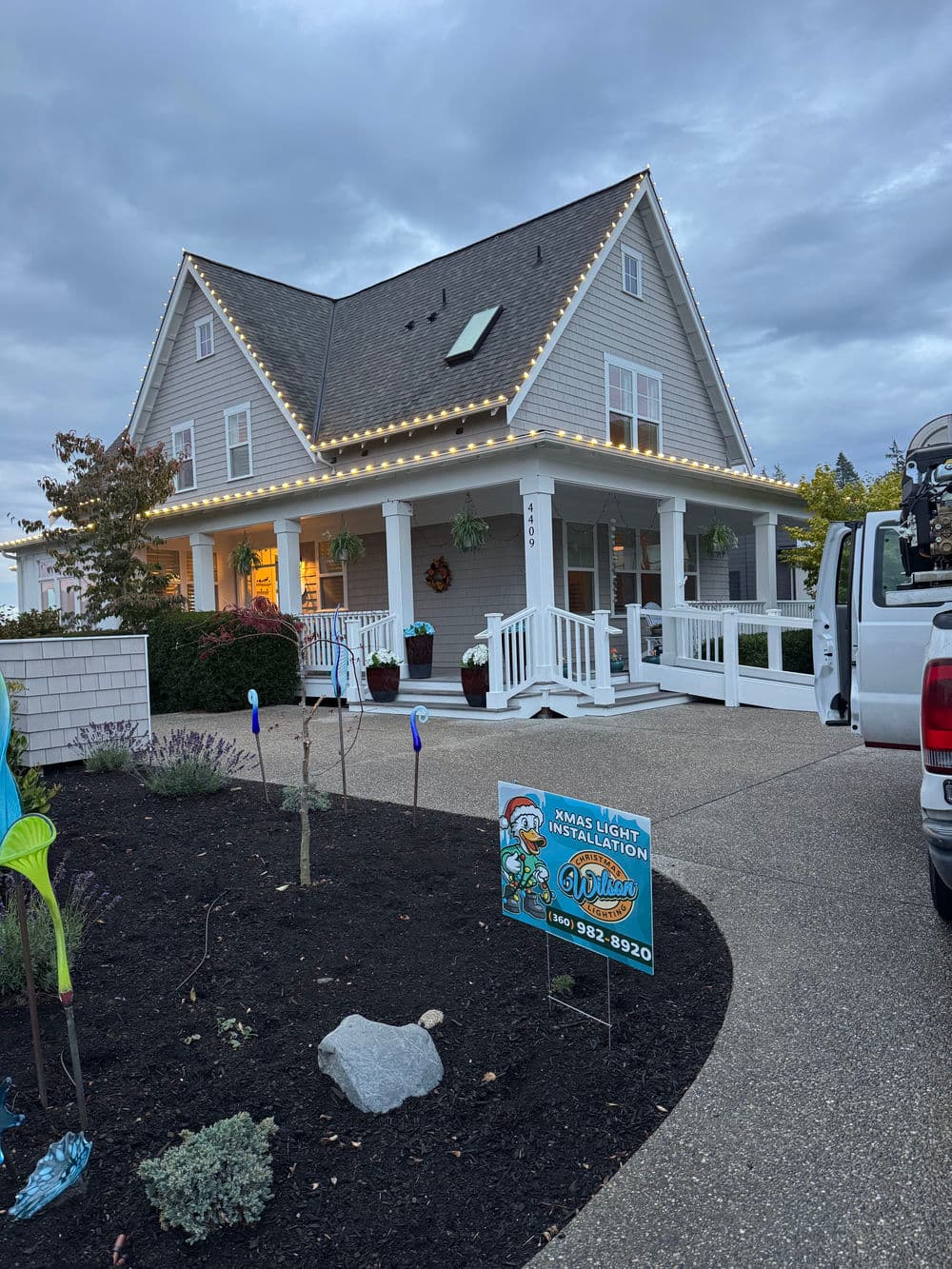 House decorated with holiday lights and a lawn sign for a local lighting installation service.