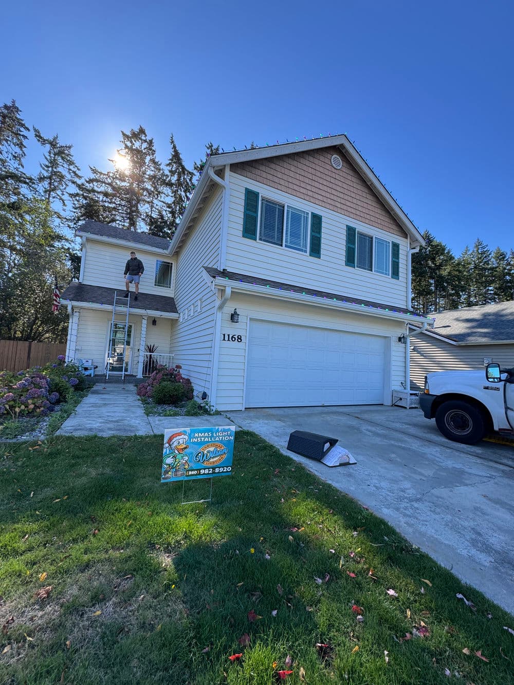 House with a ladder, worker doing maintenance, and lawn sign advertising services.