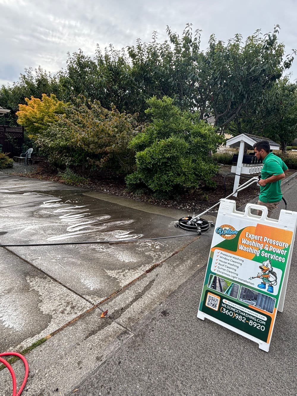 Man using pressure washer on a driveway, promoting expert washing services nearby.